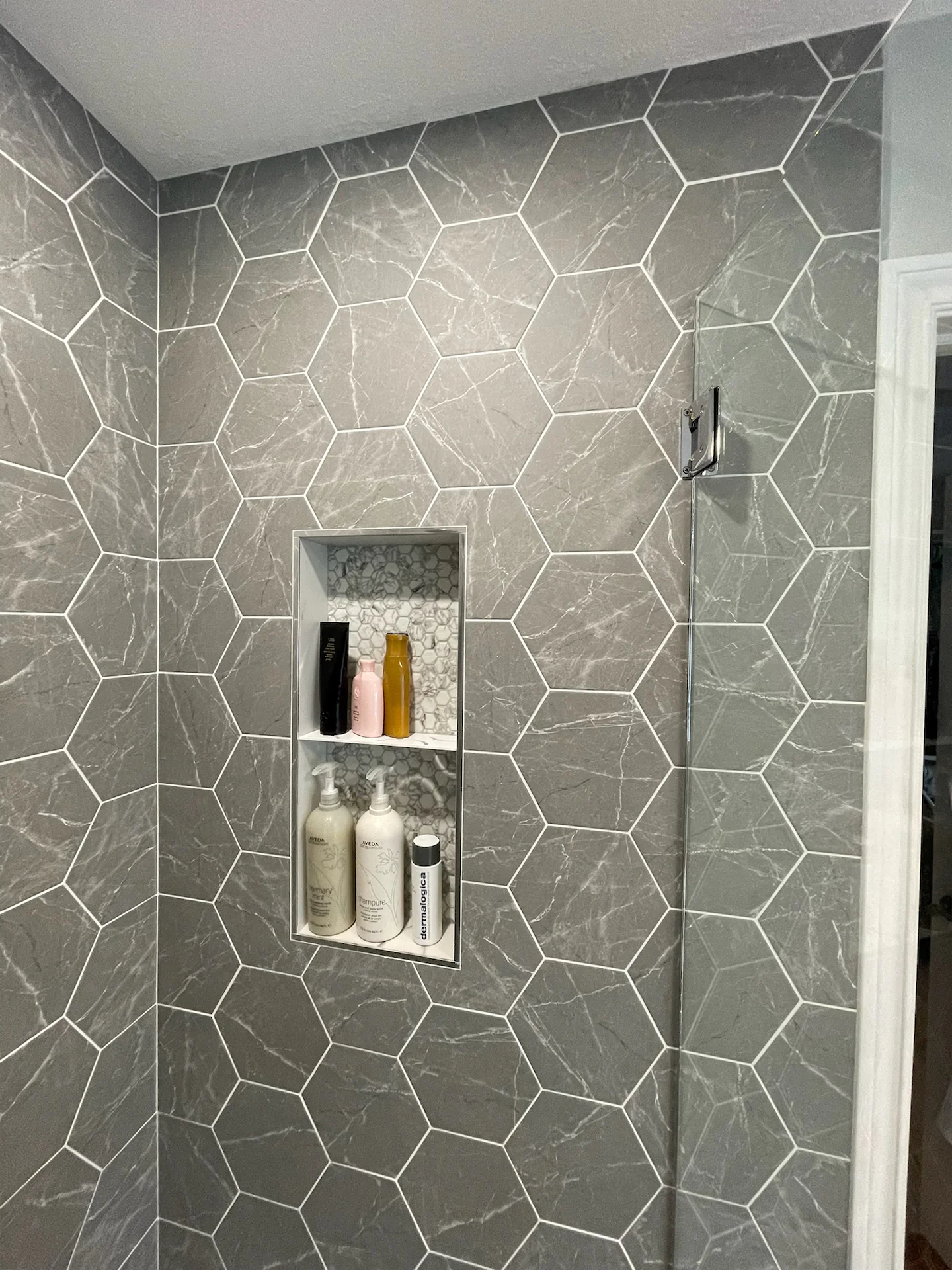completed project by tile installation specialist in Terwillegar Edmonton with Hexagonal 7x8 tile glass enclosure and niche. gorgeous finish