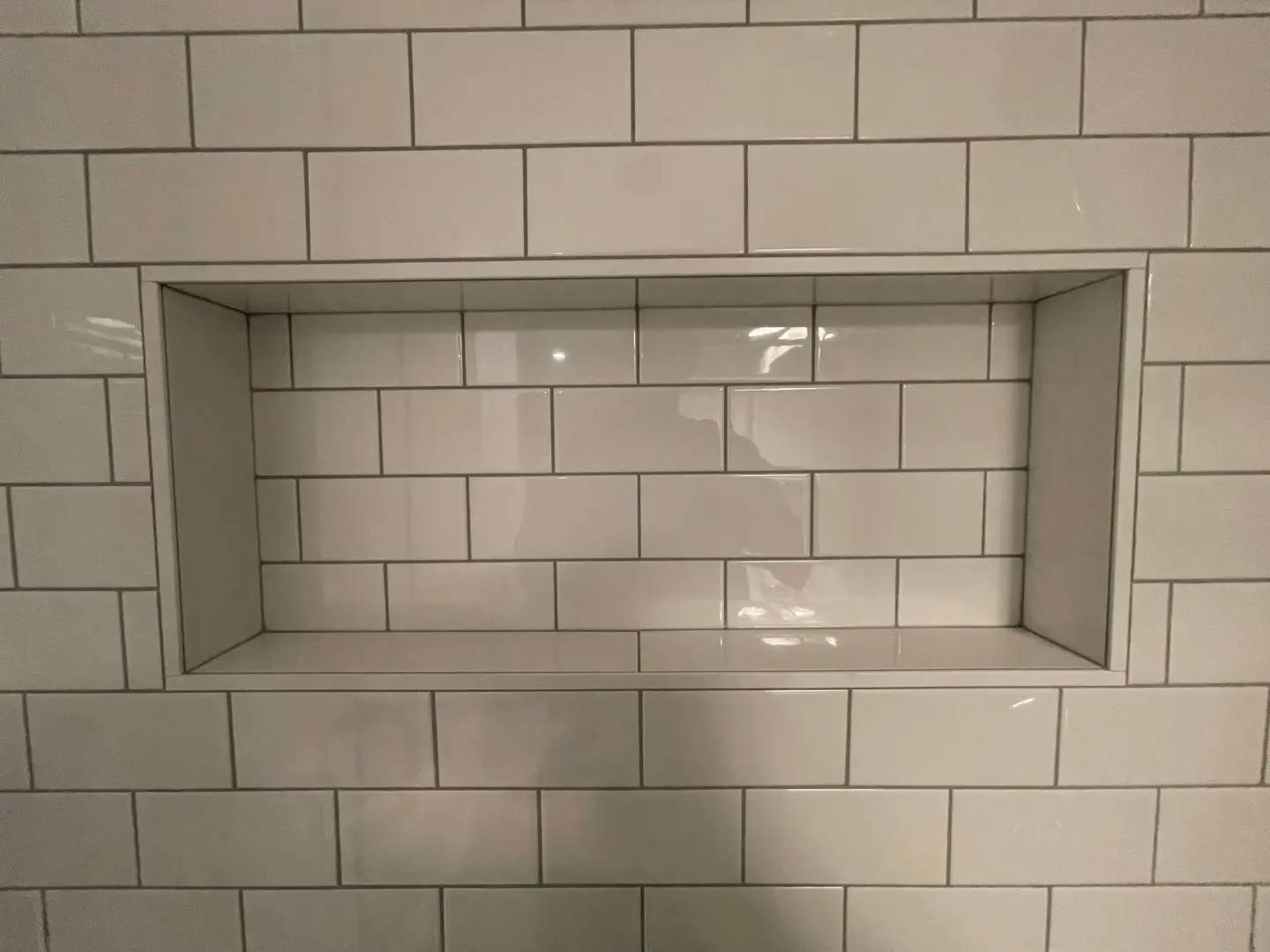 horizontal niche 3x6 subway white glossy tile with white grout and white matte trim completed by tile contractors in edmonton the tile experts